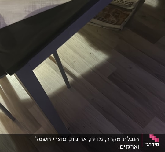 שולחן עם חפצים, ניירות ואריזות על הרצפה